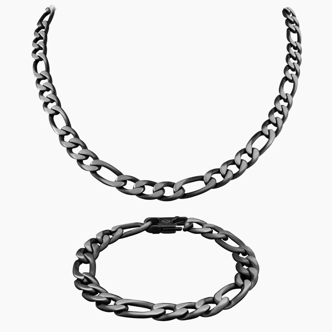 Figaro-set i mörk svart- silverfinish med halskedja och armband mot vit bakgrund – rå, stilren look.
#en:color_black,sv:farg_svart