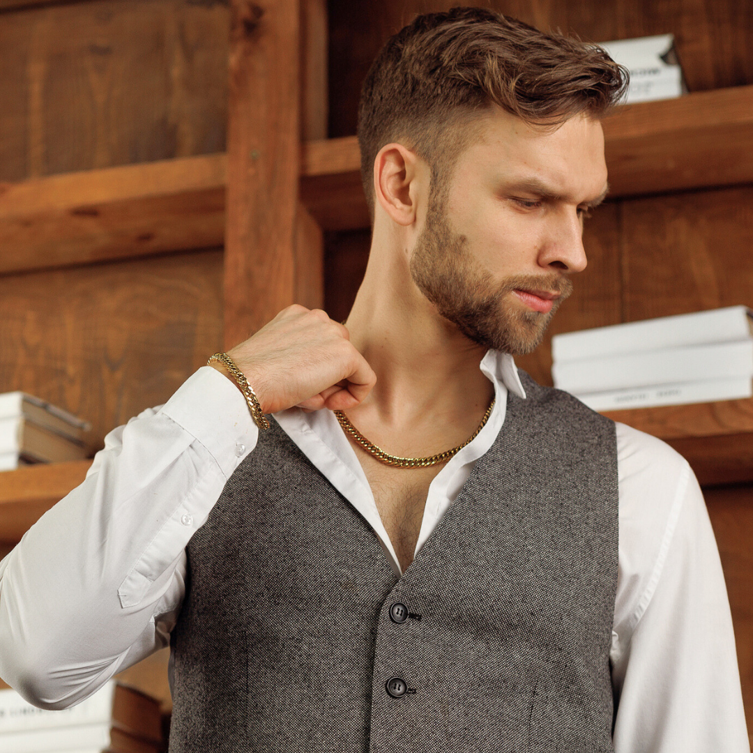 man i väst och skjorta bär kedja och armband, avslappnad men sofistikerad vibe.#en:color_gold,sv:farg_guld