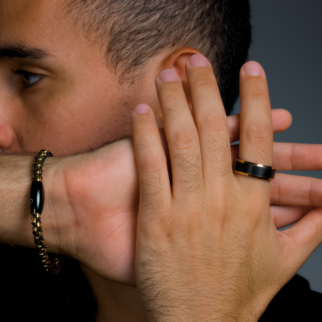 Man i profil justerar ringen på fingret, ljussättning framhäver den matta finishen.#en:color_black,sv:farg_svart