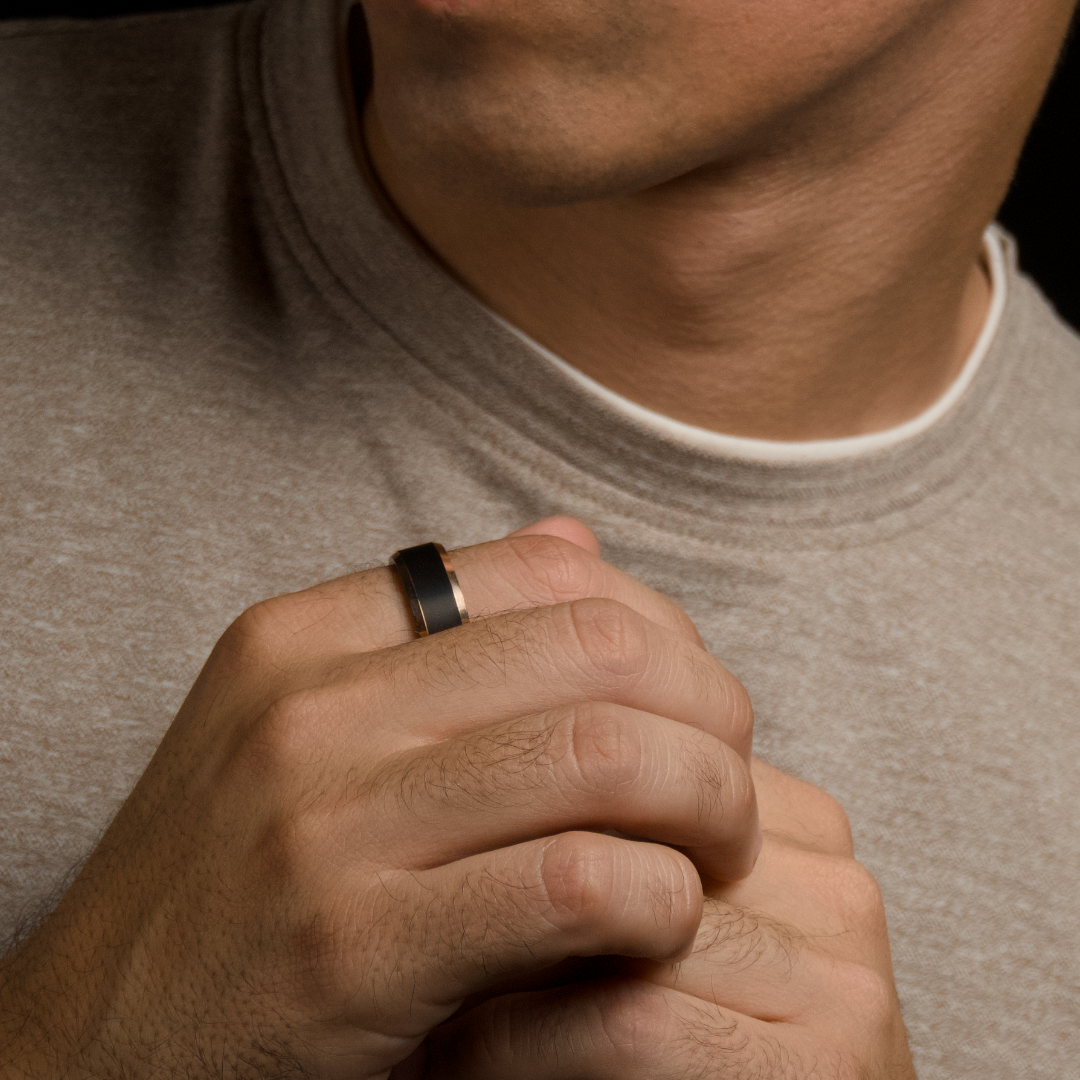 Närbild på händer som sätter på ringen, varm ton och enkel t-shirt.#en:color_black,sv:farg_svart