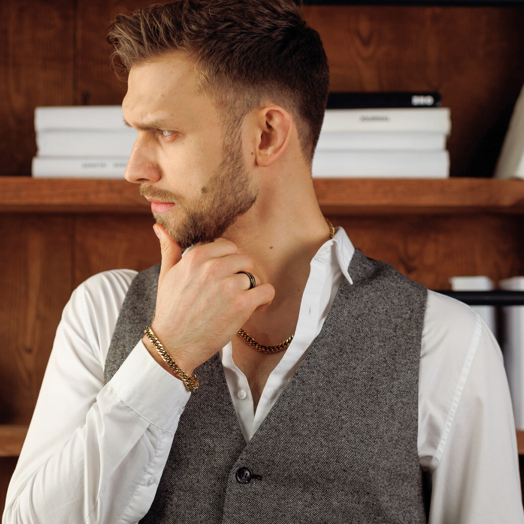 Man i väst och vit skjorta bär ringen vid ansiktet i eftertänksam pose.