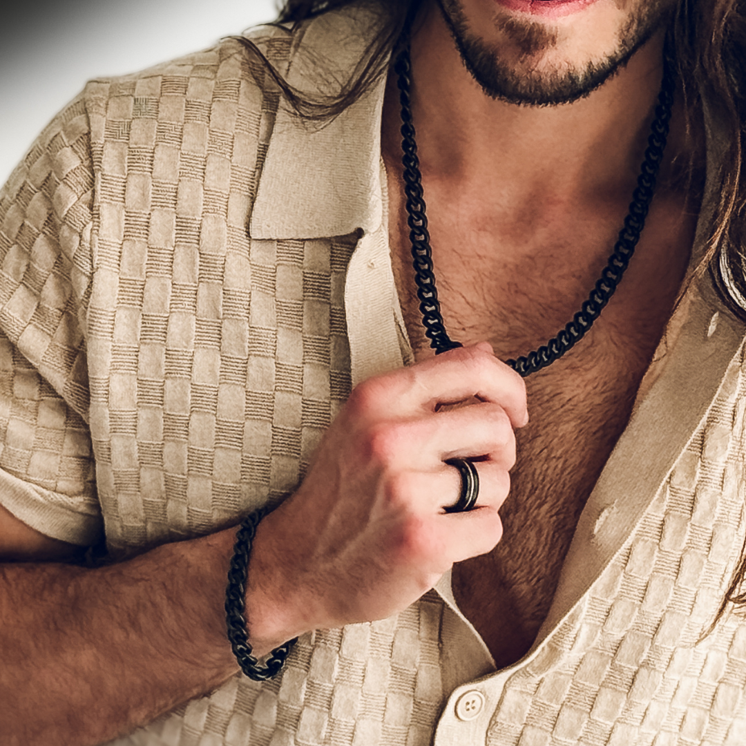 Närbild på halskedjan i svart finish, elegant kontrast mot solbrun hud.#en:color_black,sv:farg_svart