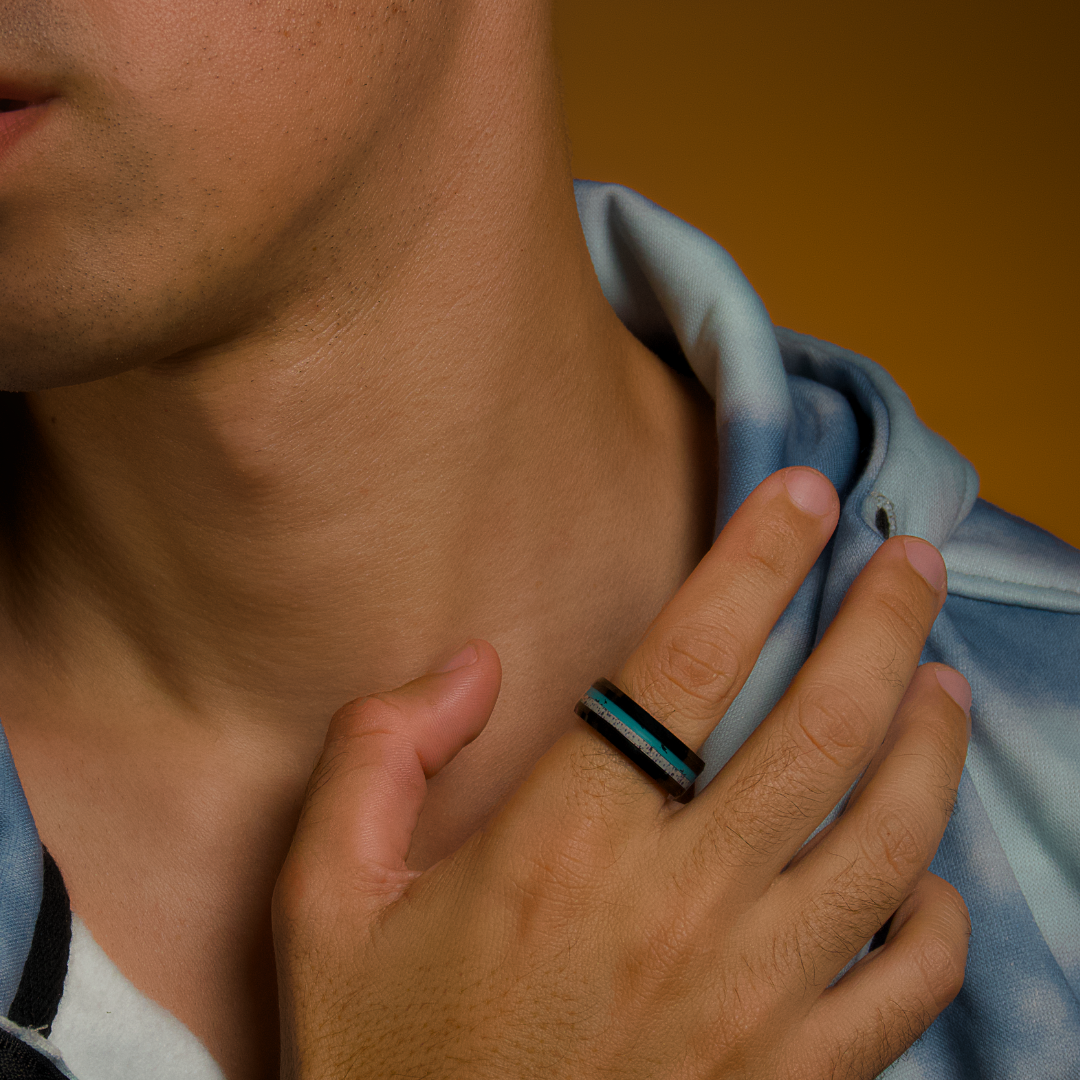 Närbild på hand vid halsen, svart ring med glittrande detaljer i centrum.