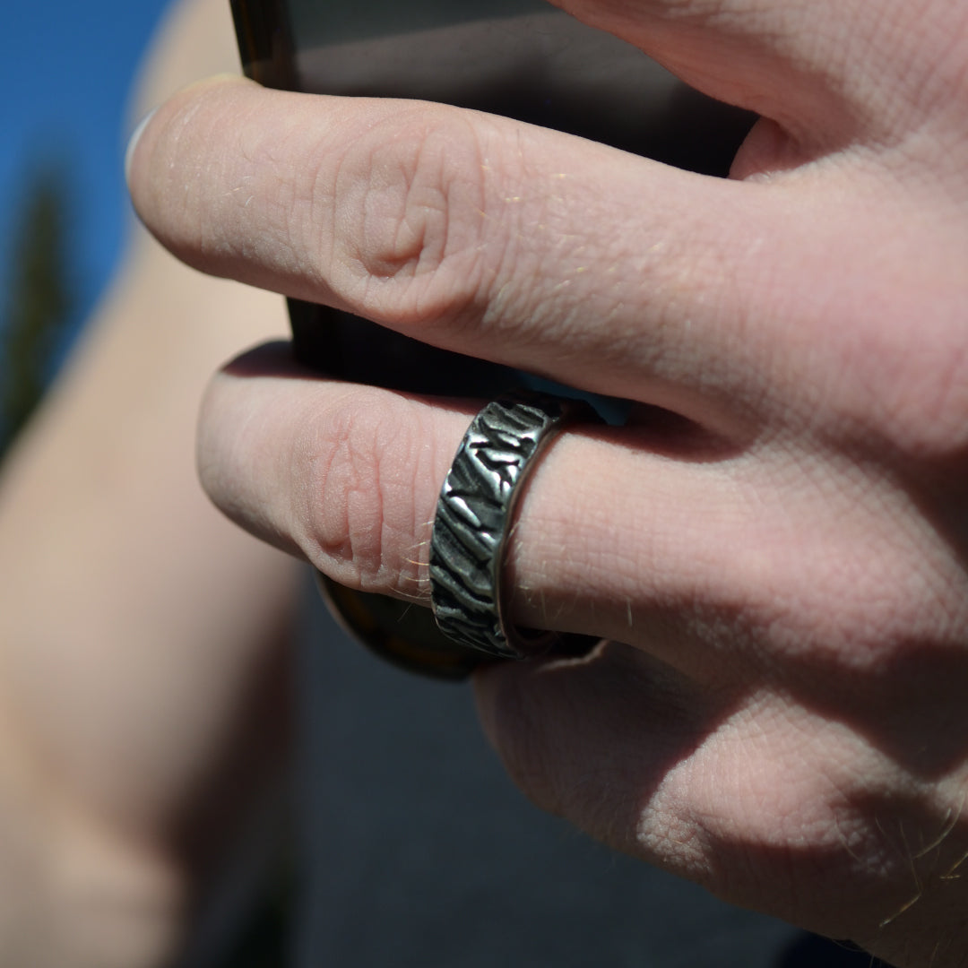 Man i sportig stil håller handen nära ansiktet, Ironbark-ringen syns tydligt.