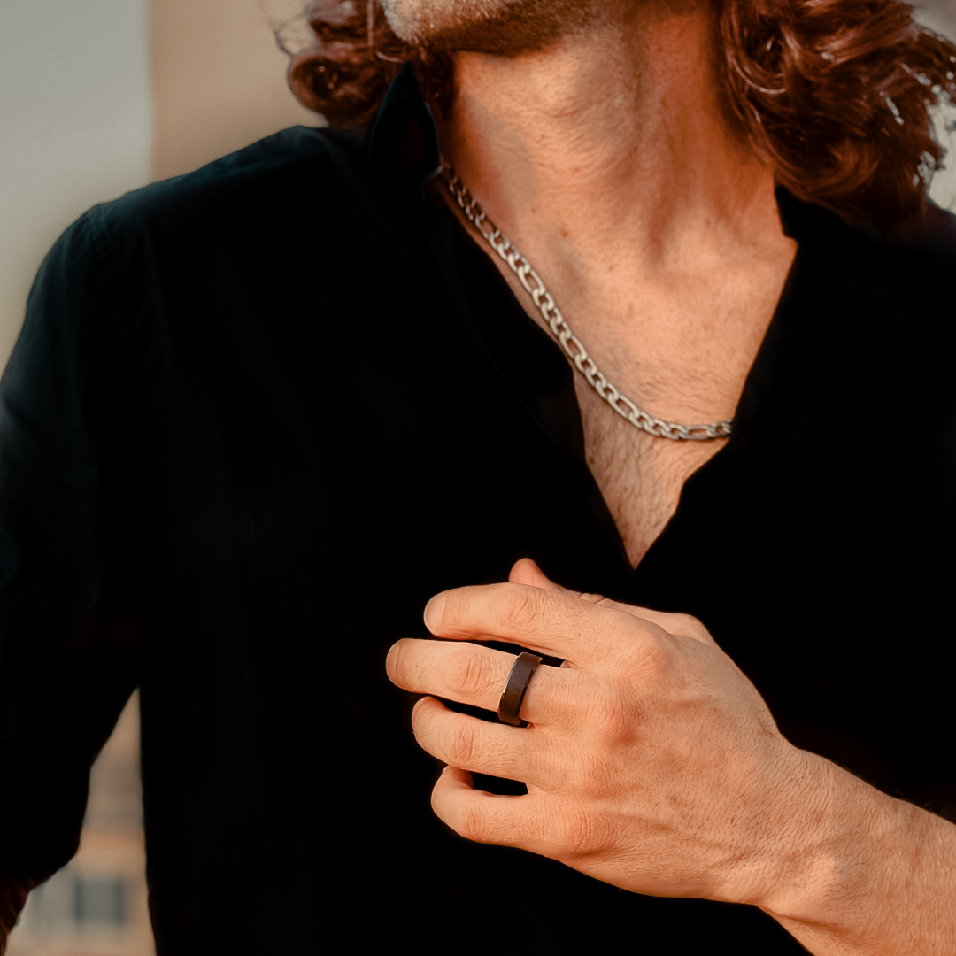 Närbild på man i svart skjorta med ring och figarokedja i stilren kombination.#en:color_silver,sv:farg_silver