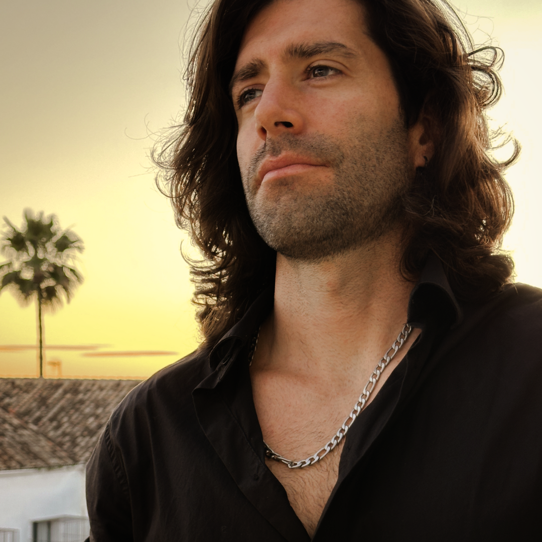 Långhårig man bär kedjan utomhus, starkt ljus ger metallisk lyster.#en:color_silver,sv:farg_silver