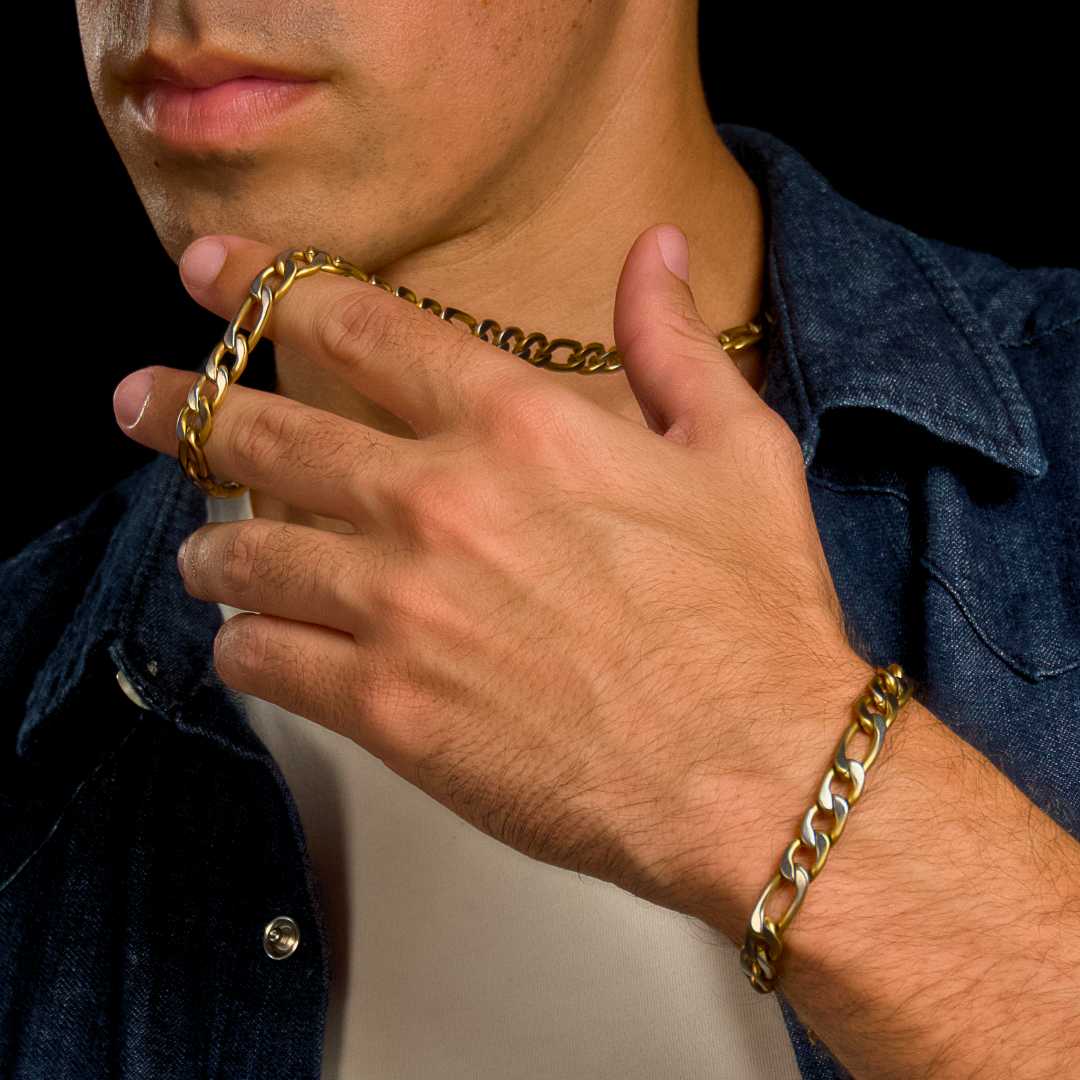 Närbild på halsband och armband i kombination – varm belysning förstärker glansen.#en:color_gold,sv:farg_guld