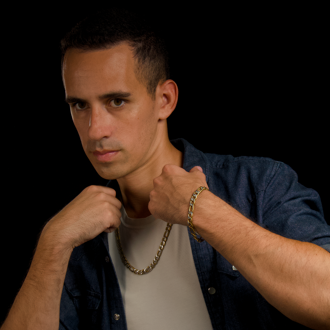 Man greppar kedjan med båda händerna, blicken fokuserad – modern, självsäker look.#en:color_gold,sv:farg_guld