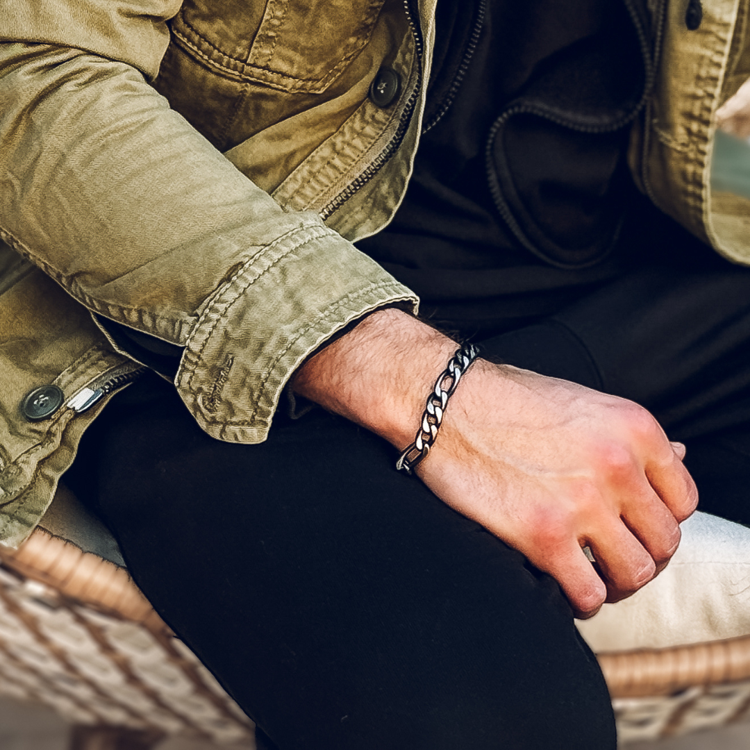 Man i grön jacka visar upp armbandet, silverlänkarna blänker mot hans hud.#en:color_black,sv:farg_svart