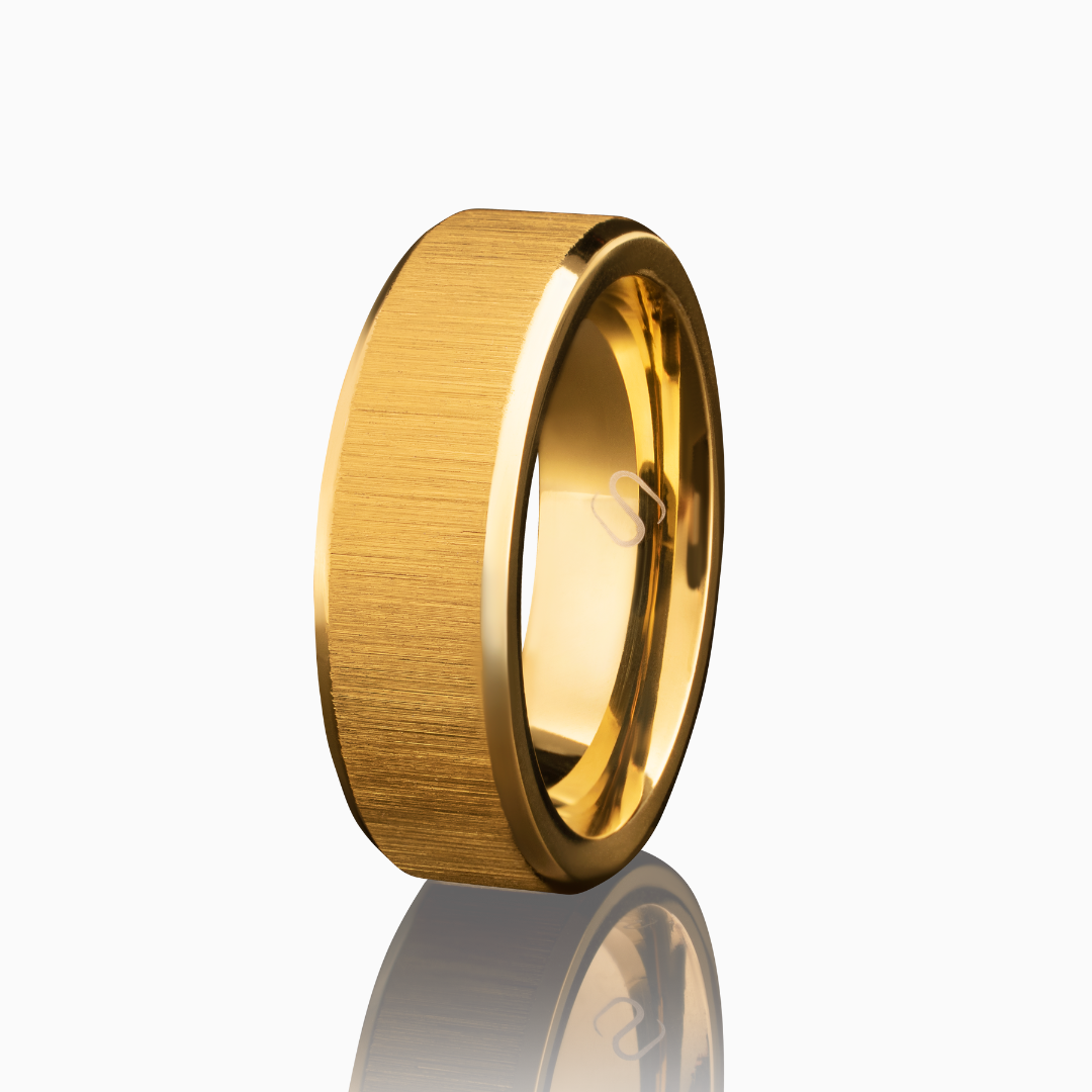 Guldfärgad ring i borstat rostfritt stål, frilagd mot vit bakgrund med mjuk skugga.#en:color_gold,sv:farg_guld