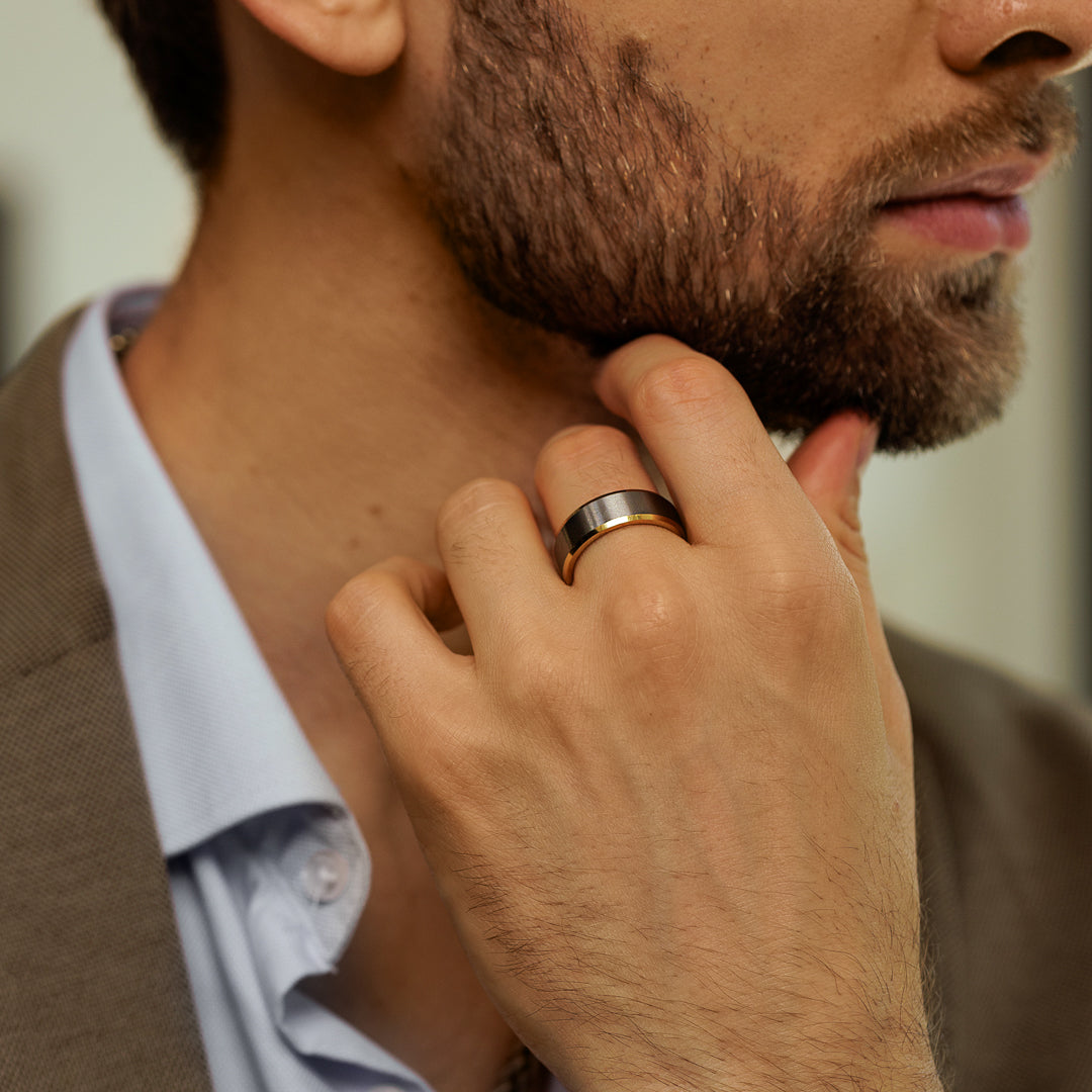 Man with a beard wearing a gold ring, close-up of hand and neck.
#en:color_silver,sv:farg_silver