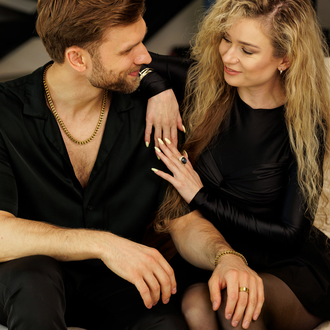 Man and woman sitting close together, both wearing black outfits.
#en:color_gold,sv:farg_guld