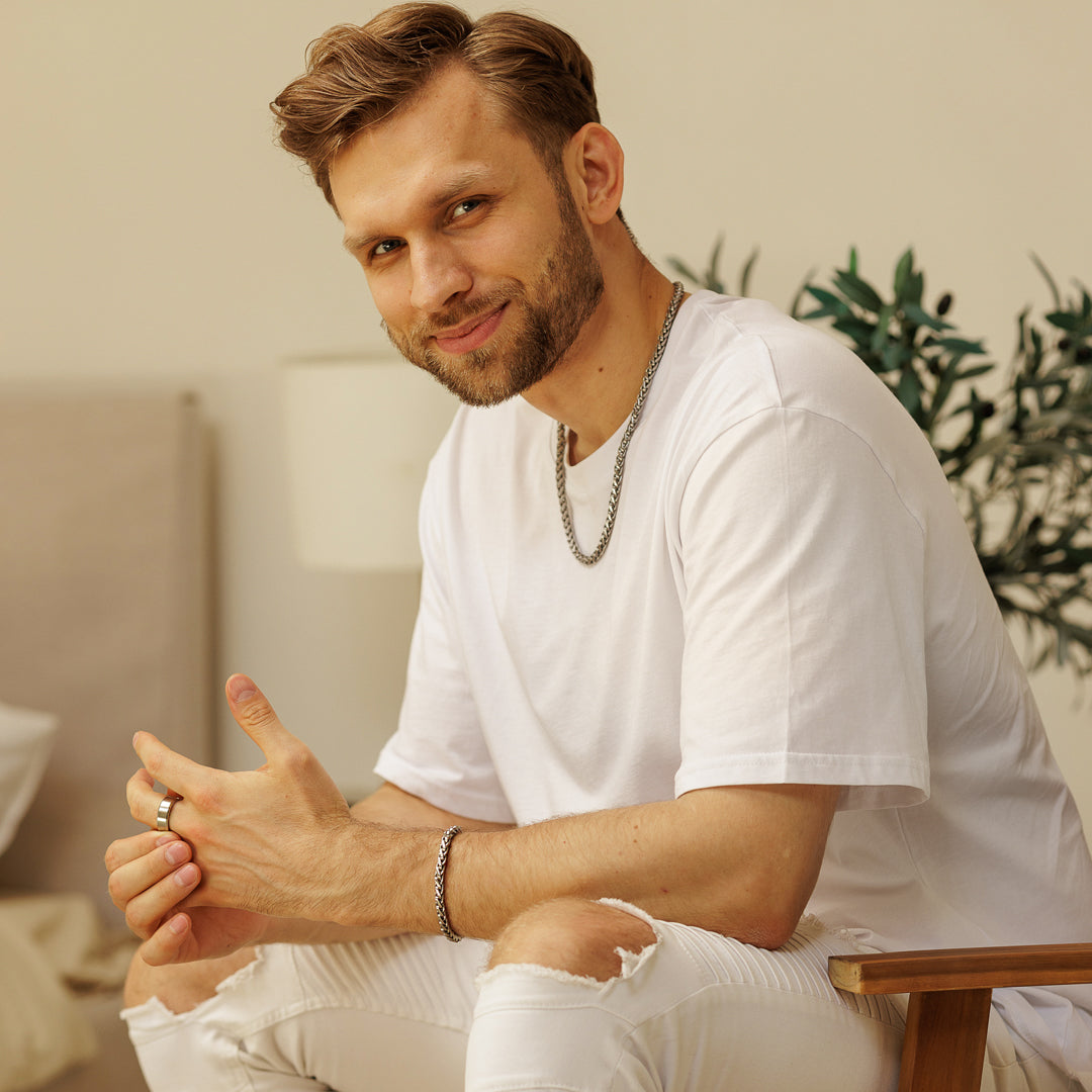 Man in a white t-shirt sitting indoors with a neutral background.
#en:color_silver,sv:farg_silver