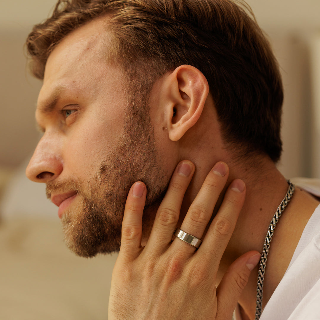 Man with a beard and a silver ring on his finger touching his neck.
#en:color_silver,sv:farg_silver