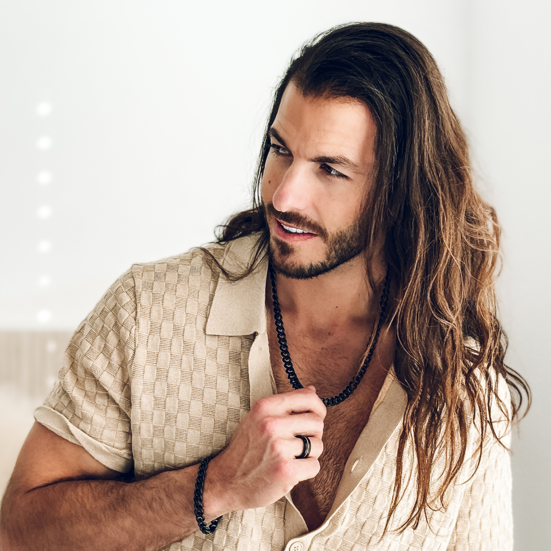 Närbild på bröstkorg med svart halskedja, skjortan lätt uppknäppt.#en:color_black,sv:farg_svart