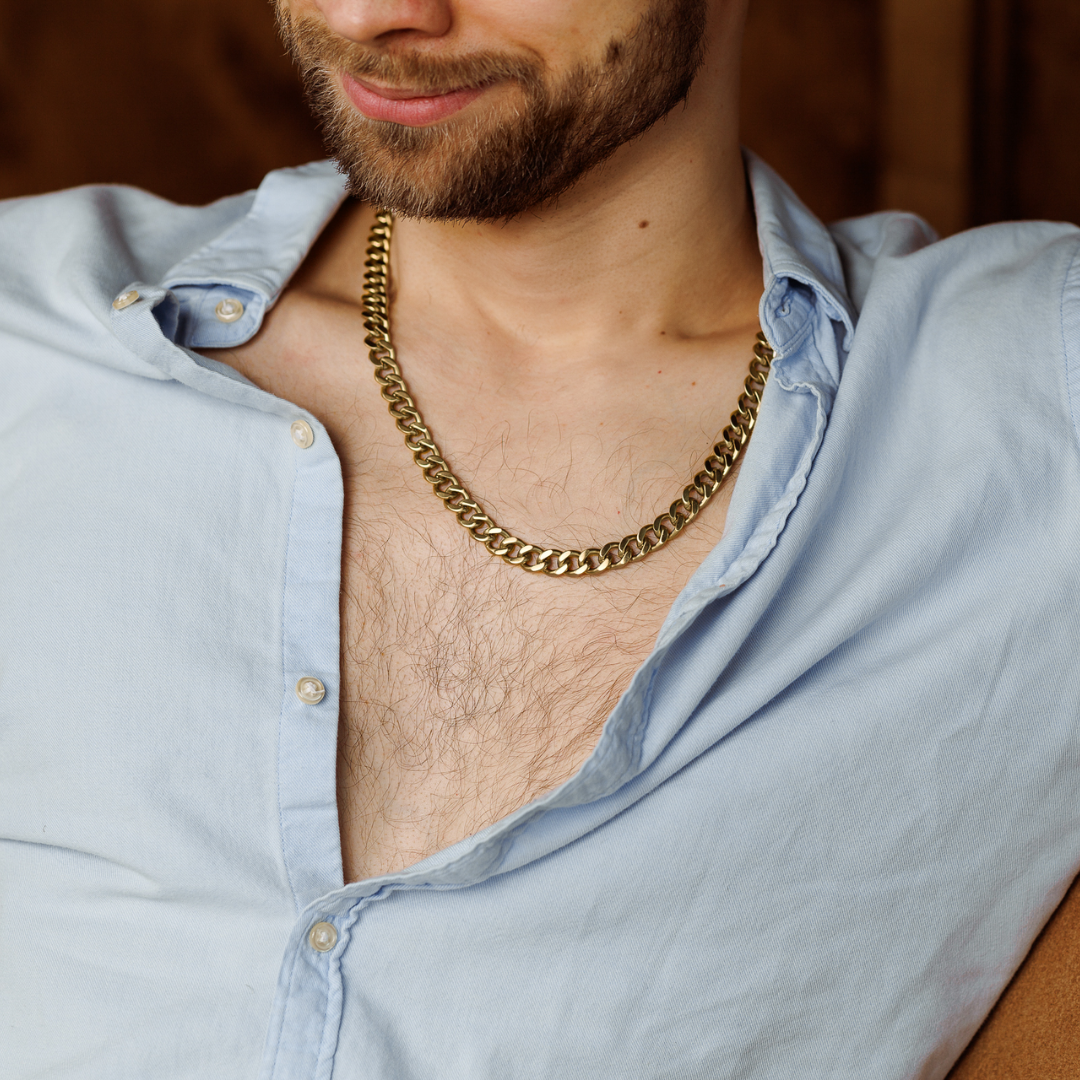 Guldkedjan visas i en rustik miljö, vilande mot öppen skjorta.#en:color_gold,sv:farg_guld