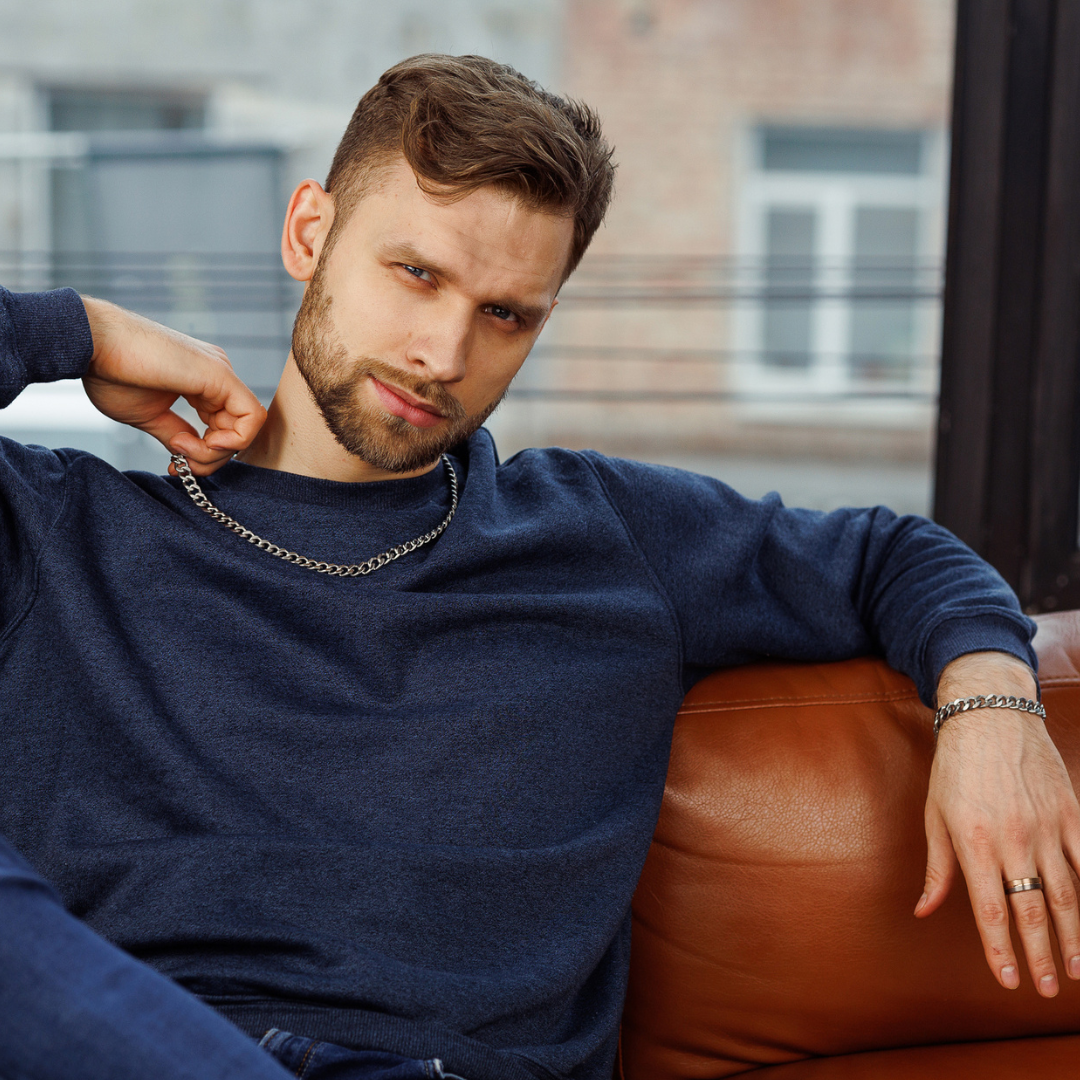 Avslappnad porträttbild med man i läderfåtölj och svart kubansk länk runt halsen.#en:color_silver,sv:farg_silver