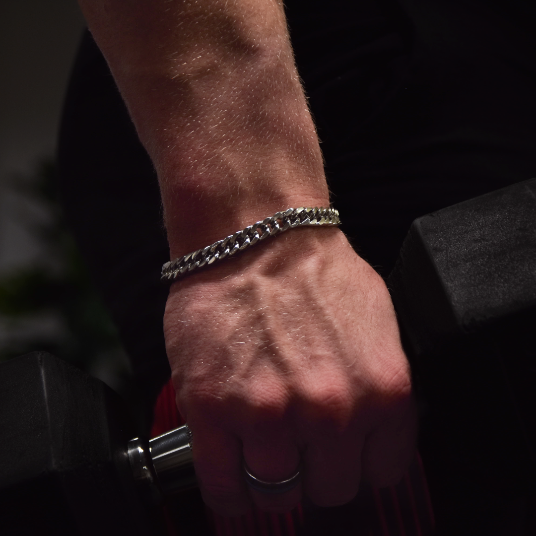 Man bär armbandet på gymmet, metallisk glans mot svettig hud – robust känsla.#en:color_silver,sv:farg_silver