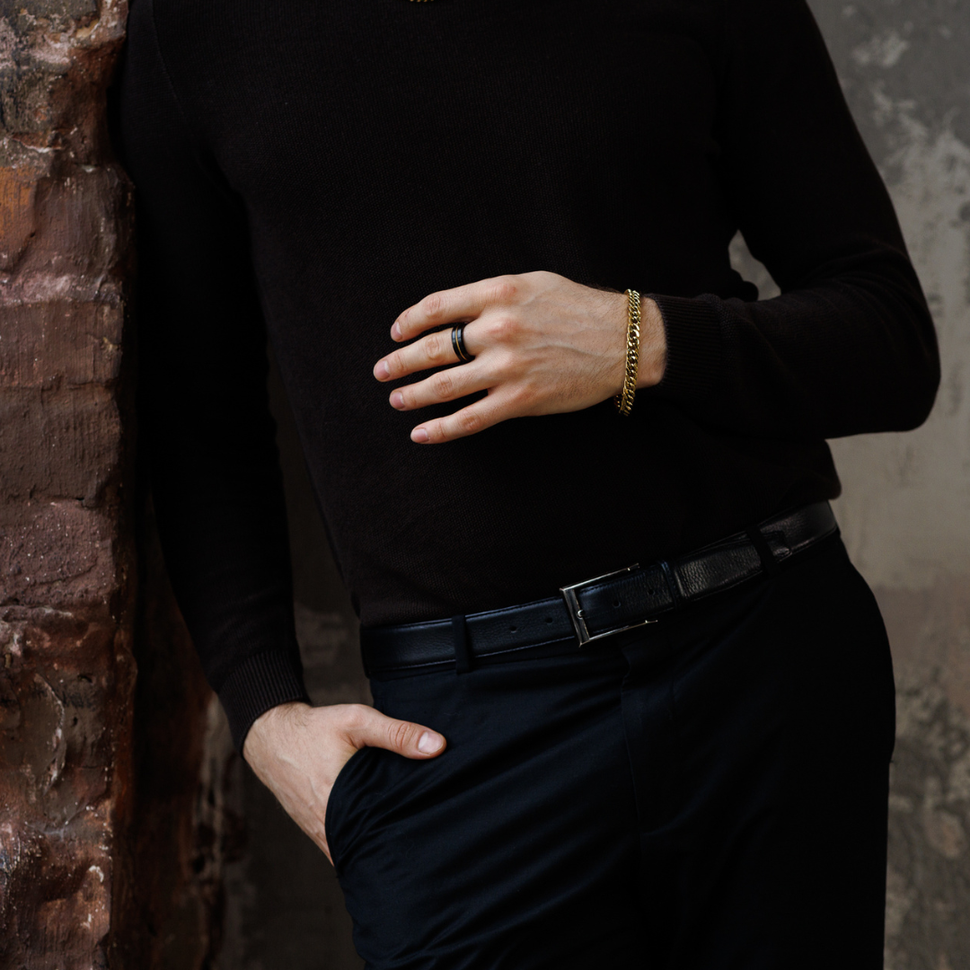 Hand placerad på höften, guldarmbandet bryter av mot helsvart look.#en:color_gold,sv:farg_guld