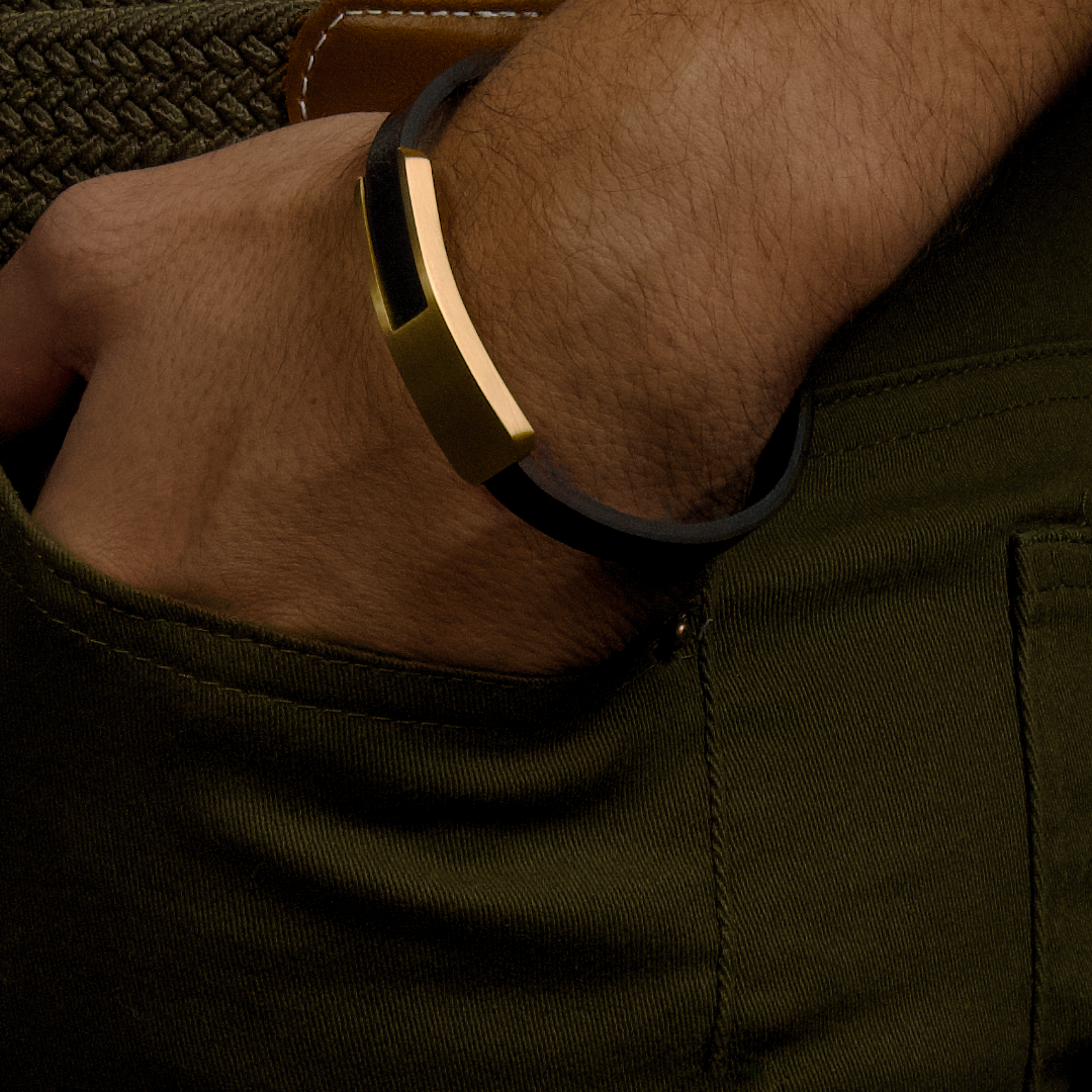 Man bär armbandet till mörkgrön byxa, guldaccenter ger en elegant kontrast.#en:color_gold,sv:farg_guld