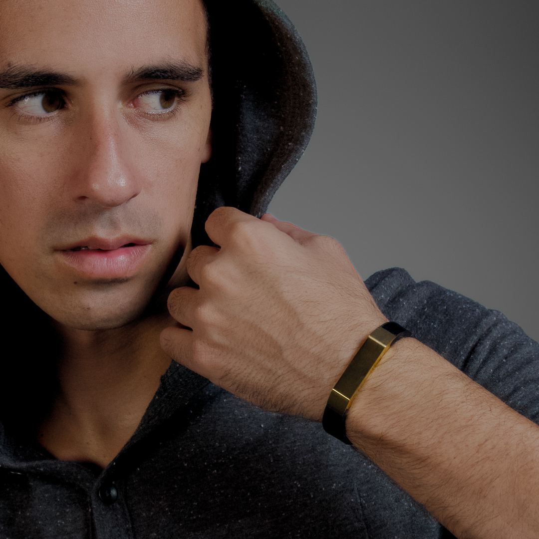 Man lutar huvudet mot handen, armbandet syns tydligt i fokus mot grå bakgrund.
#en:color_gold,sv:farg_guld