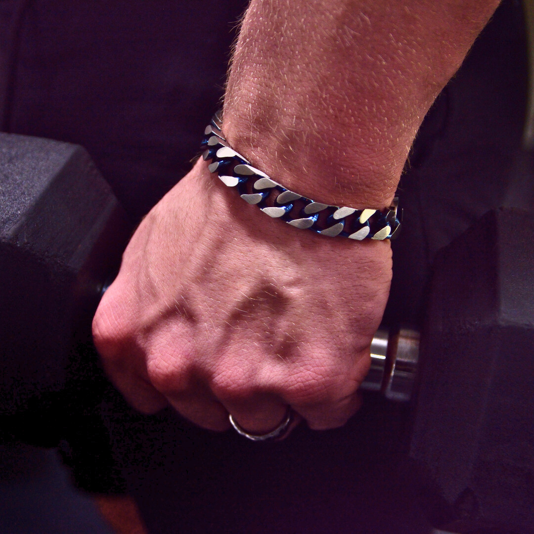 Hand greppar hantel, armbandet glimmar i metalliskt blått och silver.#en:color_blue,sv:farg_bla