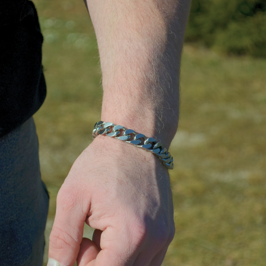 Närbild på armen med armbandet i fokus, jeans och t-shirt i bakgrunden.#en:color_silver,sv:farg_silver