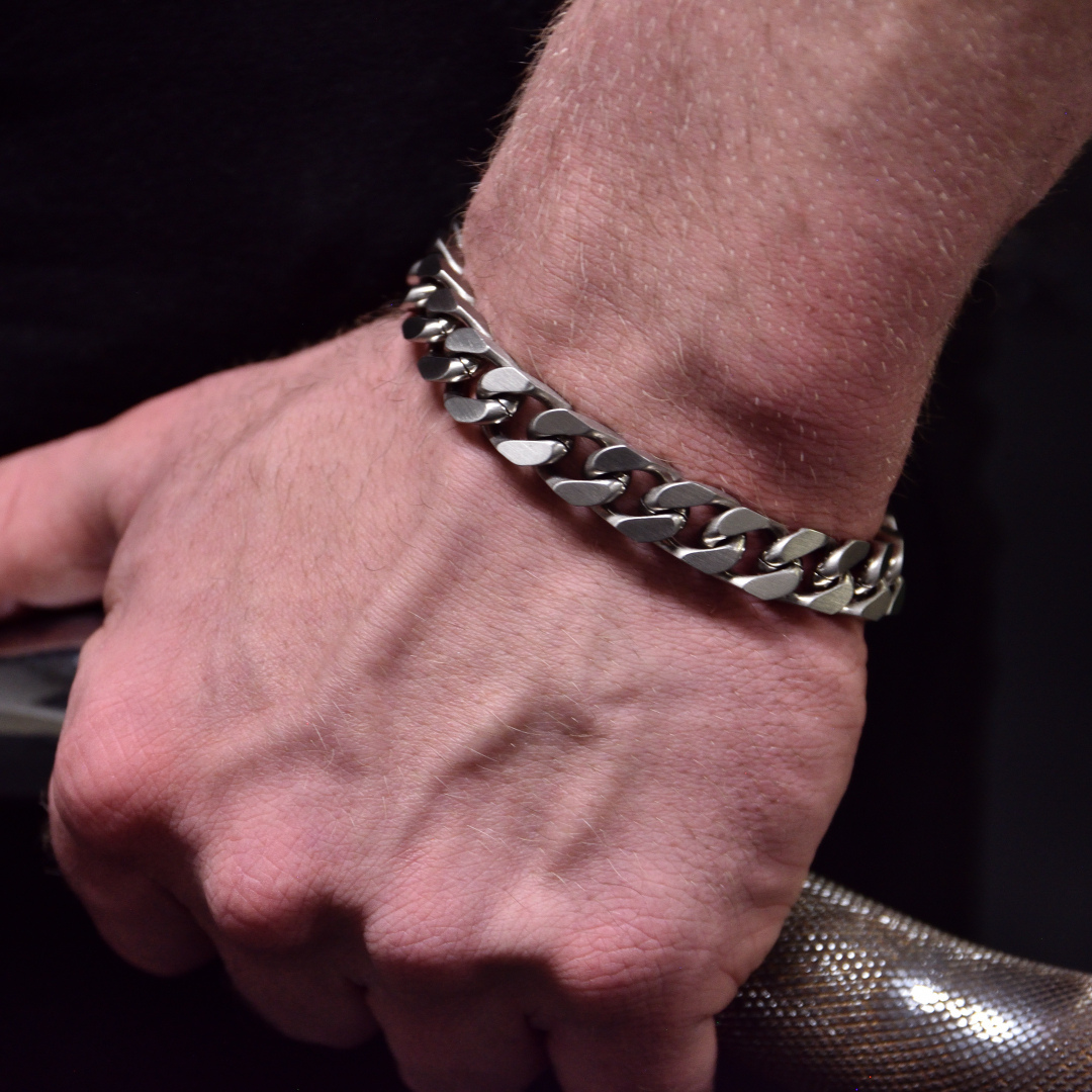 Armbandet bärs över handled i gymmiljö, greppar hantel.#en:color_silver,sv:farg_silver