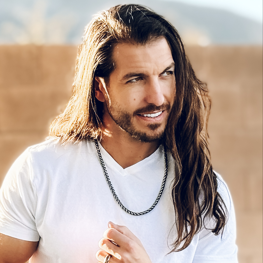 Närbild i solnedgång – mannen håller i kedjan som vilar mot bröstet.
#en:color_black,sv:farg_svart