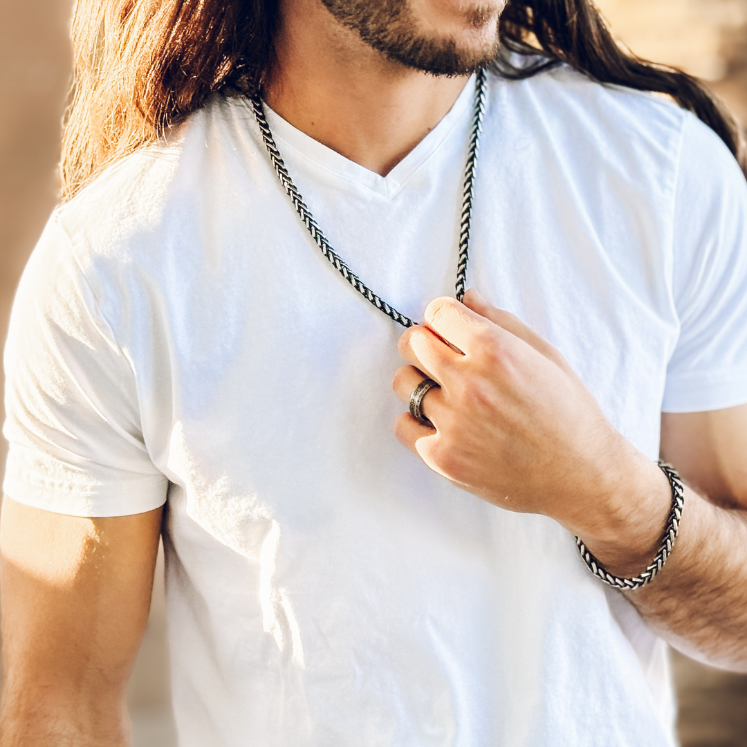 Kedjan syns tydligt mot vit t-shirt, enkel och stilren styling.#en:color_black,sv:farg_svart