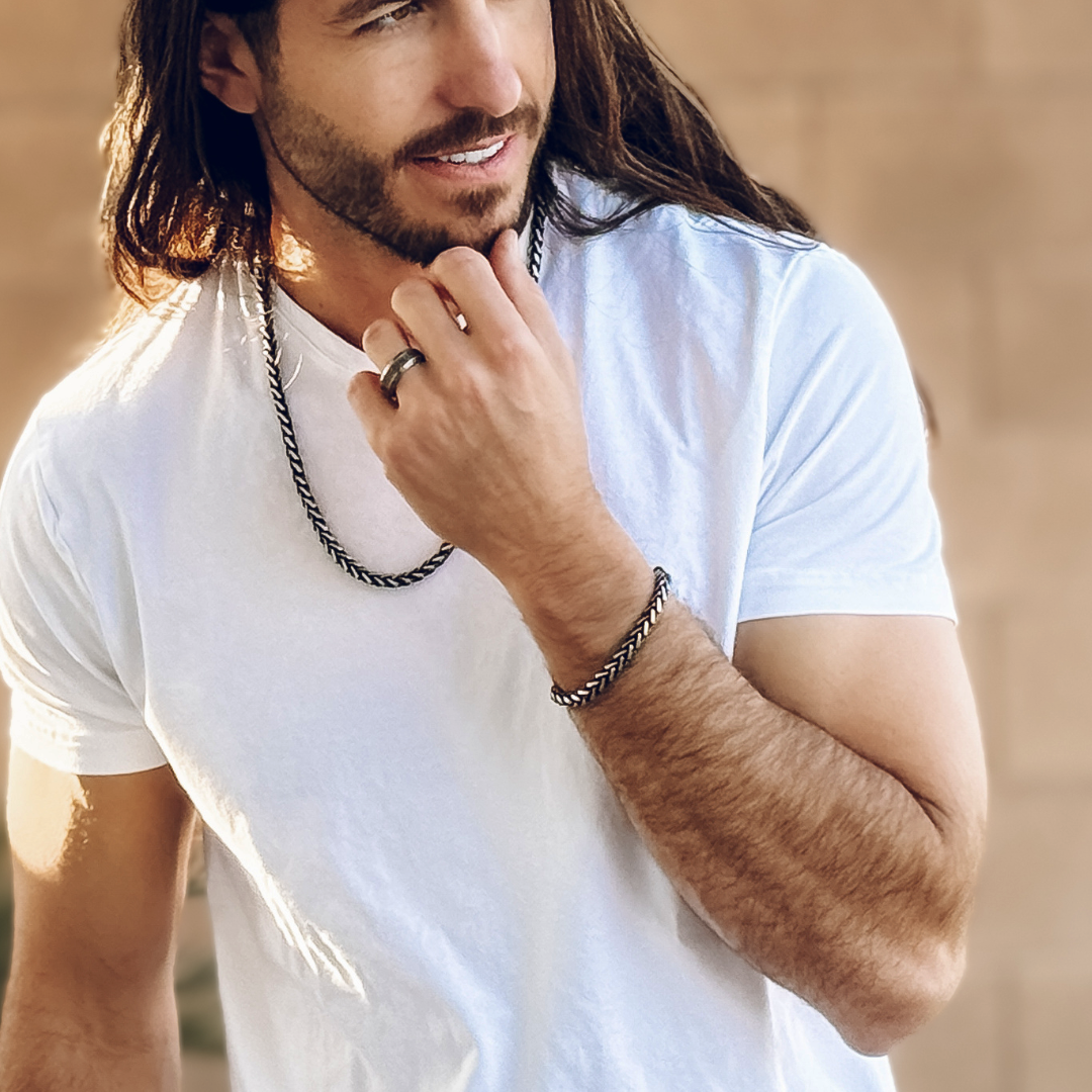 Halskedjan i fokus när handen lyfts mot hakan – detaljerad länkdesign med attityd.#en:color_black,sv:farg_svart