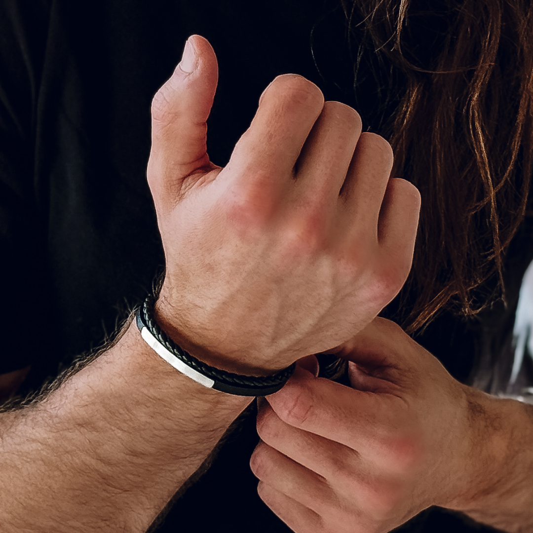 Närbild på man som håller sin handled, armbandet ger en rå och stilren look.#en:color_silver,sv:farg_silver