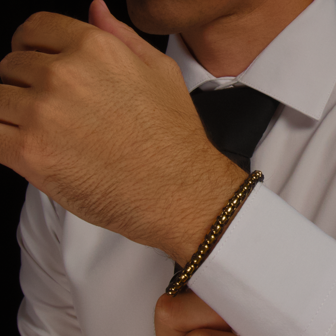 Armbandet i fokus när handen vilar mot bröstet – stilfull detalj i helhetsintrycket.#en:color_gold,sv:farg_guld