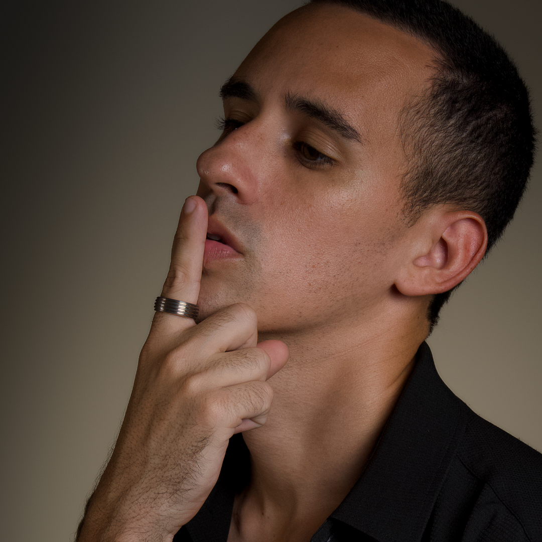 Man poserar fundersamt med stilren ring i fokus, varm studiobelysning.