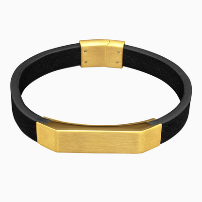 Svart läderarmband med bred gulddetalj mot vit bakgrund – kraftfull och elegant stil.