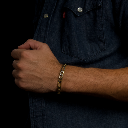 Närbild på man som justerar skjortan, armbandet framhävs i varm belysning.

