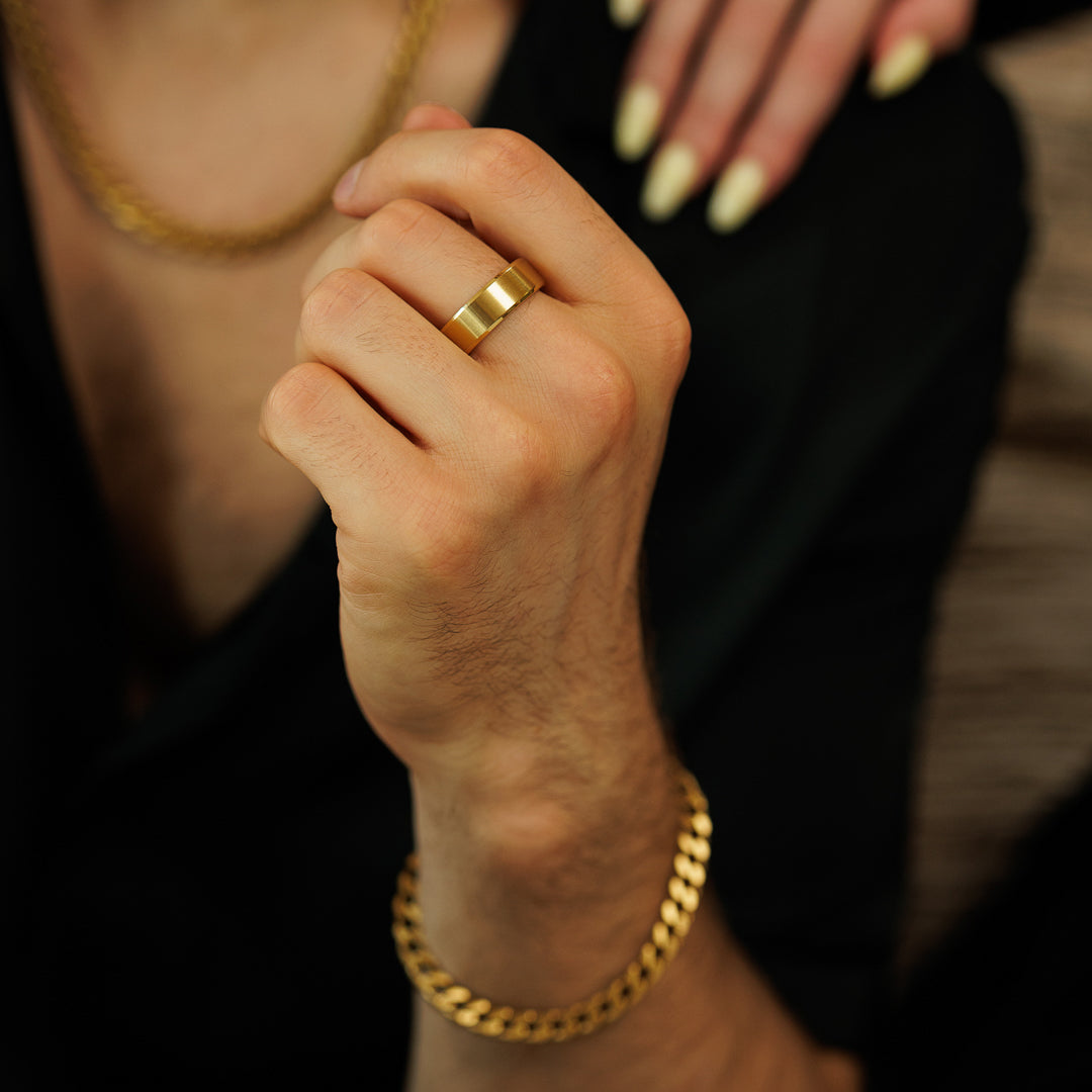 Close-up of a hand wearing a gold ring and bracelet with a blurred background.
#en:color_gold,sv:farg_guld