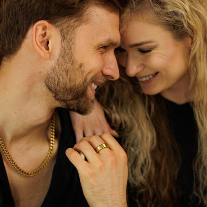 Man and woman with close-up of hands and gold rings, warm lighting.
#en:color_gold,sv:farg_guld