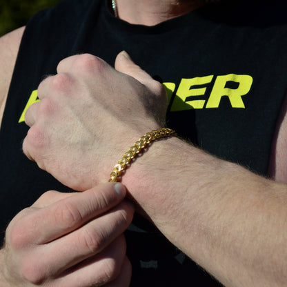 Guldfärgat armband på muskulös handled, mot svart t-shirt med neongul text.
