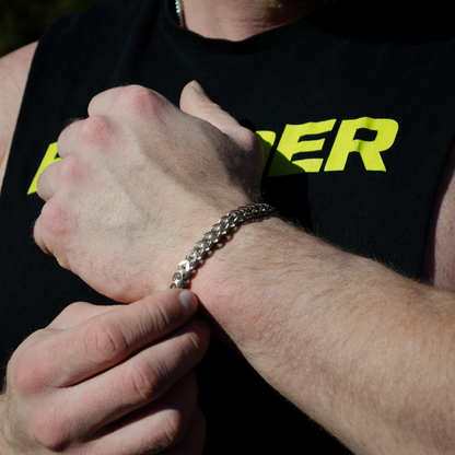 Hand över hand, silverarmbandet ligger tajt runt handleden, t-shirten säger "POWER".
