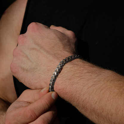 Tränad man bär armbandet i svart t-shirt, kedjan syns tydligt mot huden.