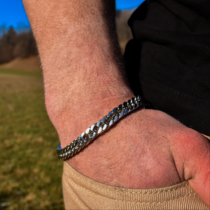 Handled med kedjearmband i solsken, casual stil med naturelement i bakgrunden.