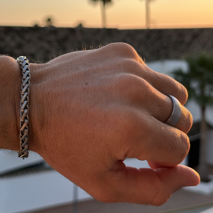 Närbild på hand som bär både silverring och armband vid solnedgång.