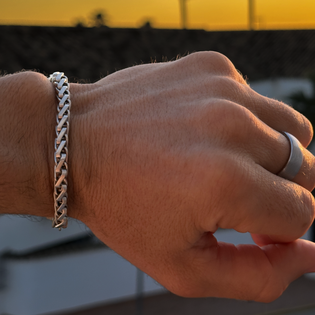 Närbild på hand med silverarmband i solnedgång, varm ton och snygg kontrast.#en:color_silver,sv:farg_silver