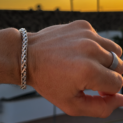 Närbild på hand med silverarmband i solnedgång, varm ton och snygg kontrast.