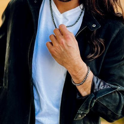Man i vit t-shirt och svart jacka bär setet – urban stil med maskulin känsla.
