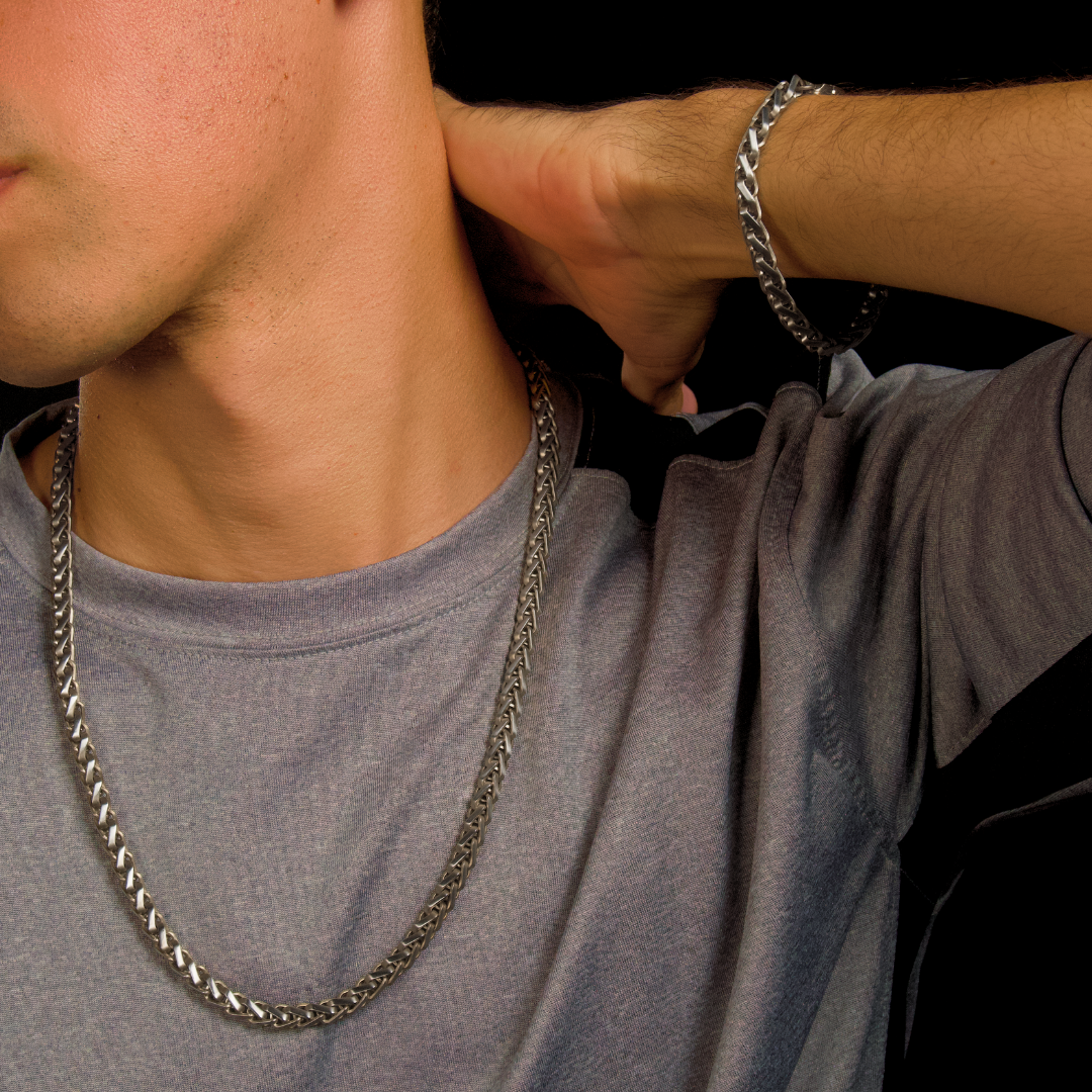 Man i grå t-shirt med kedjan synlig runt halsen – avslappnad stil med metallisk edge.#en:color_silver,sv:farg_silver