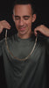 Videoikon över man som poserar med kedjan i spotlight, minimalistisk bakgrund.
#en:color_gold,sv:farg_guld