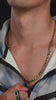 Man bär Arctic Glimmer-ringen nära halsen som bär figaro halsband.